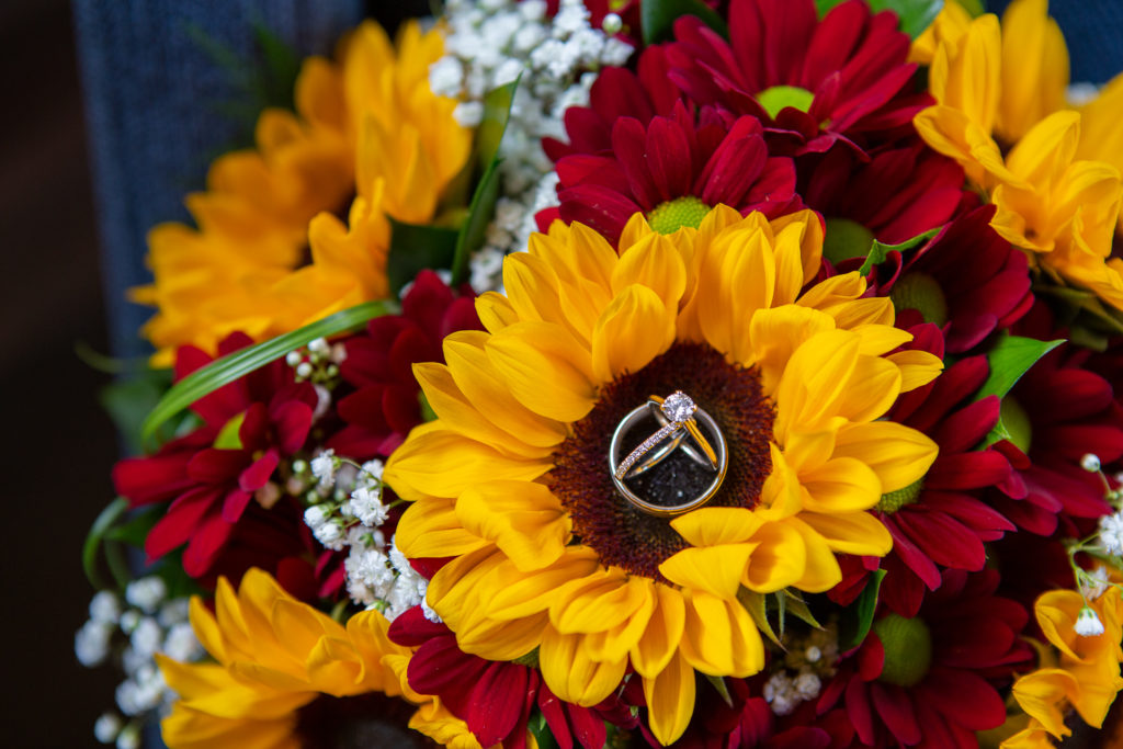 wedding rings on a sunflower bouquet at fall wedding at the barn