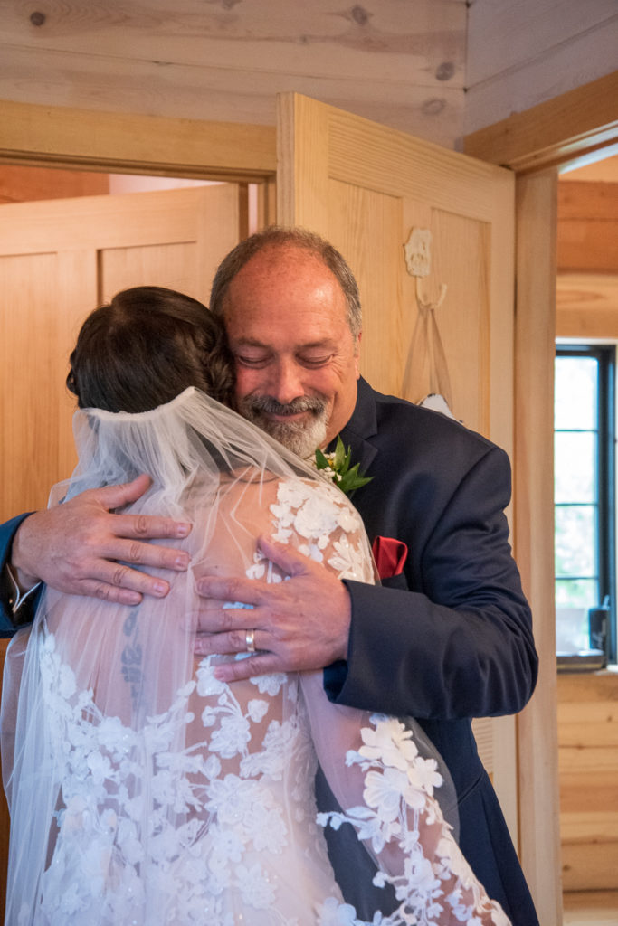 dad hugs bride after first look at fall wedding at the barn