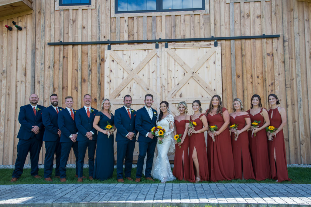 bridal party in front of the barn at wedding rings on a sunflower bouquet at fall wedding at the barn