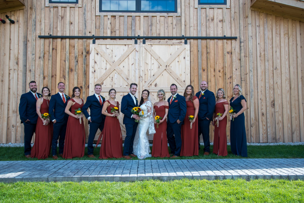 bridal party in navy & burnt orange at wedding rings on a sunflower bouquet at fall wedding at the barn
