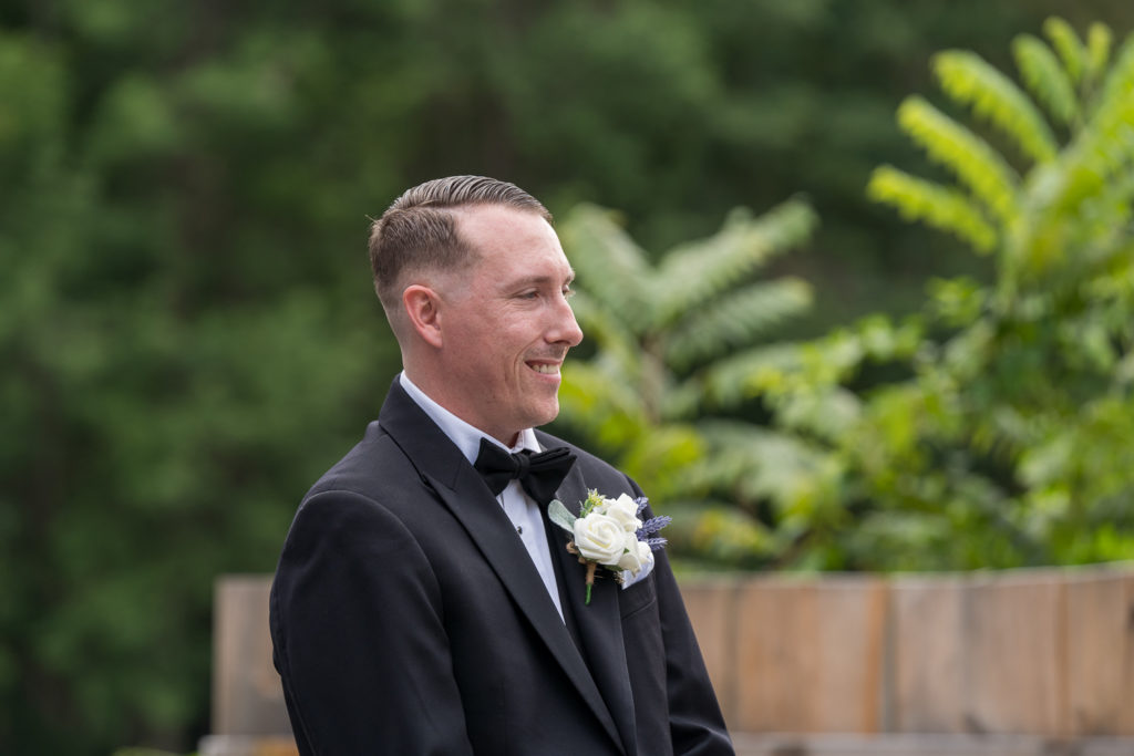 Derek & Tiffany (bride and groom) wedding - Derek smiling as he sees his bride walking down the aisle