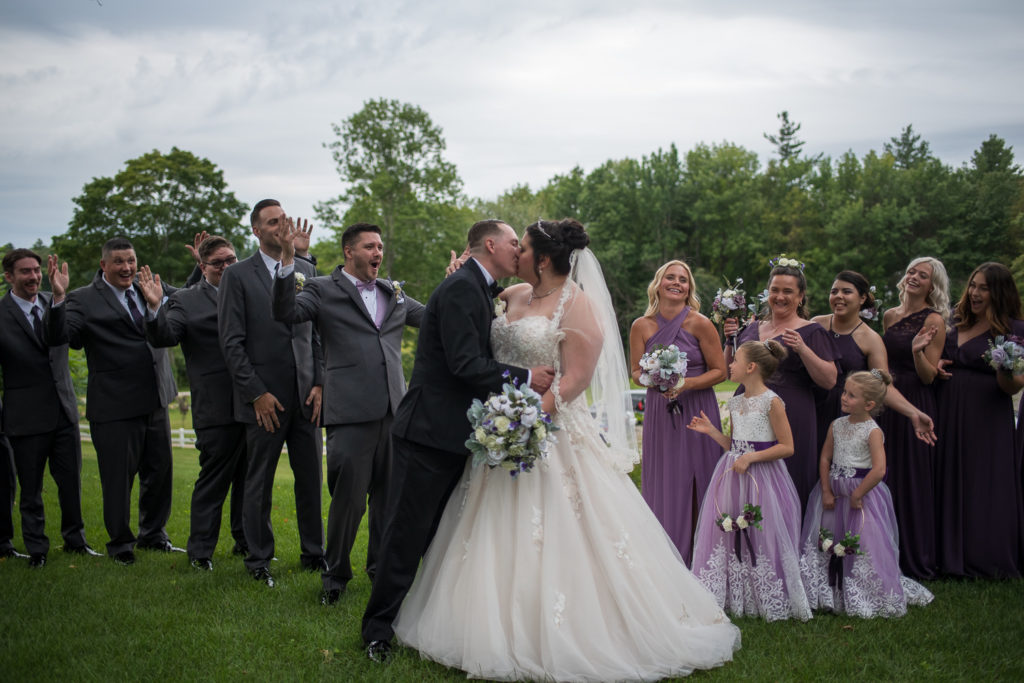 Derek & Tiffany (bride and groom) wedding - bride and groom kissing while their bridal party cheers