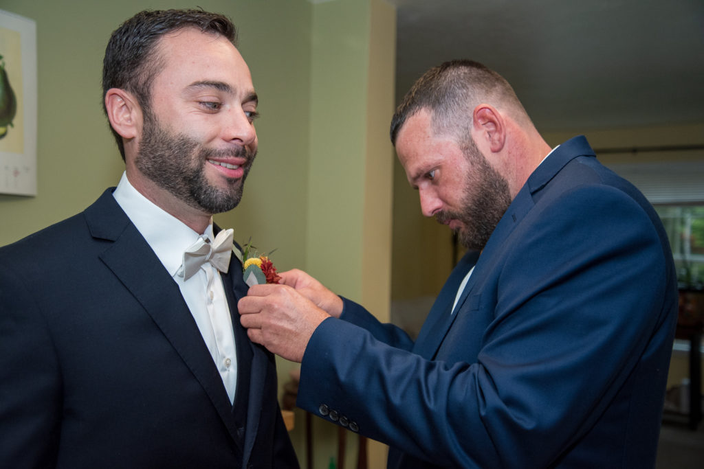 groomsmen putting on the groom's boutonniere