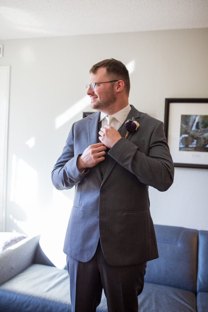 groom fixing his tie while looking out the window