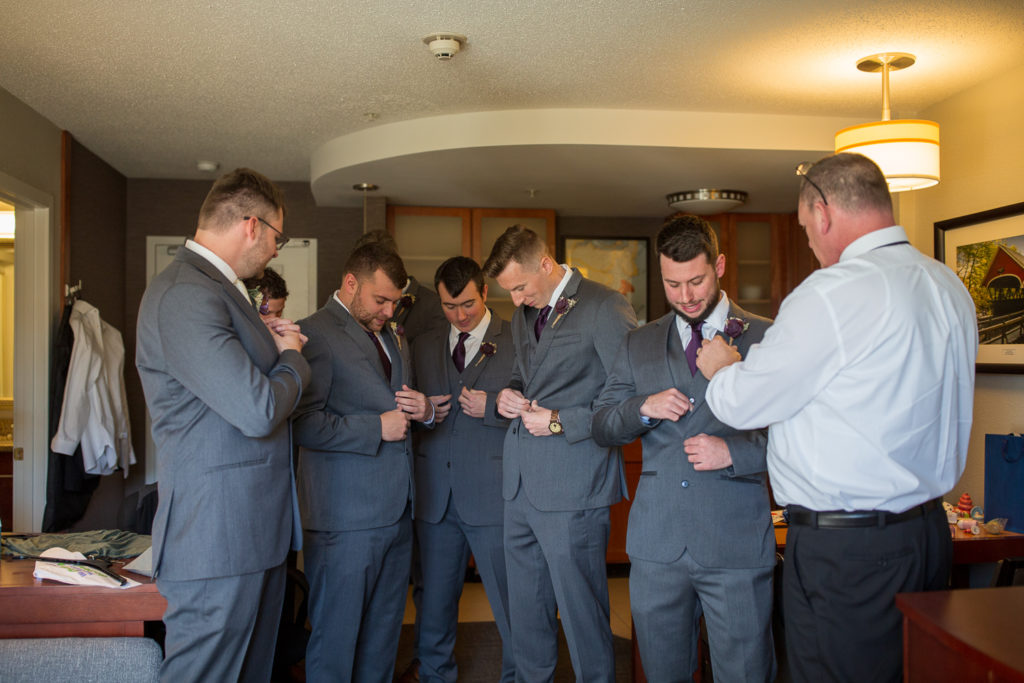 groom and groomsmen buttoning their jacket