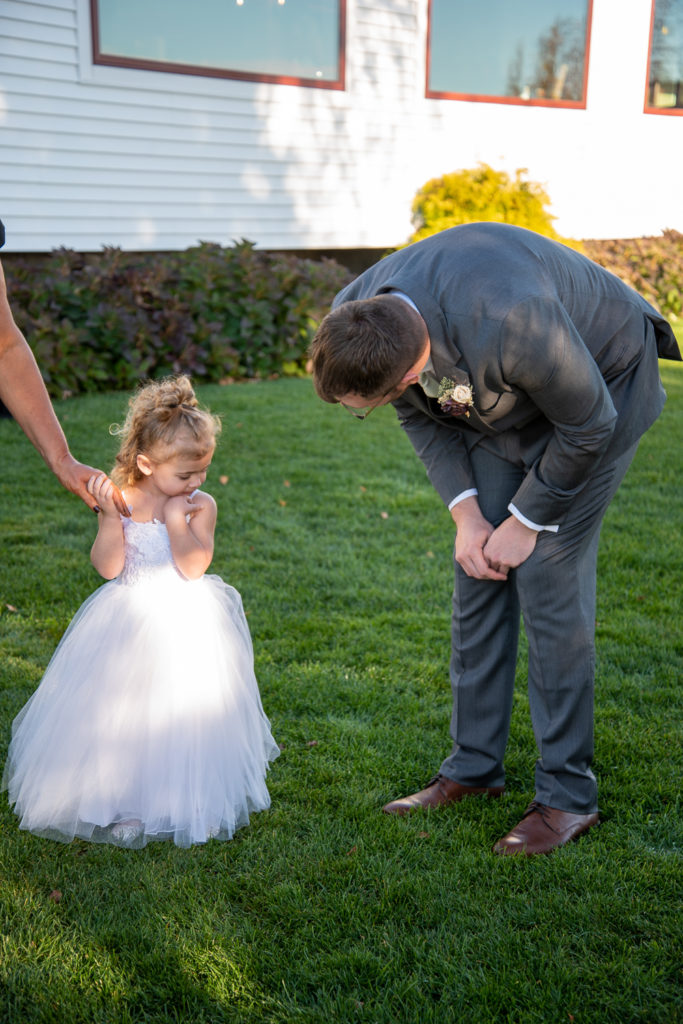 groom having a first look with the 2 year old flower girl, his niece
