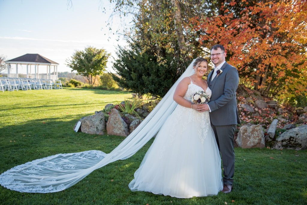 bride and groom by a fountain and beautiful orange foliage tree at the perfect fall wedding