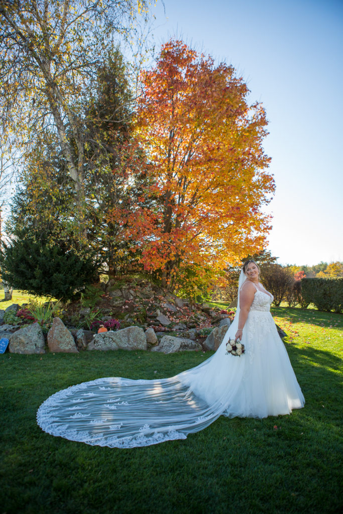 bride by a fountain and beautiful orange foliage tree at the perfect fall wedding