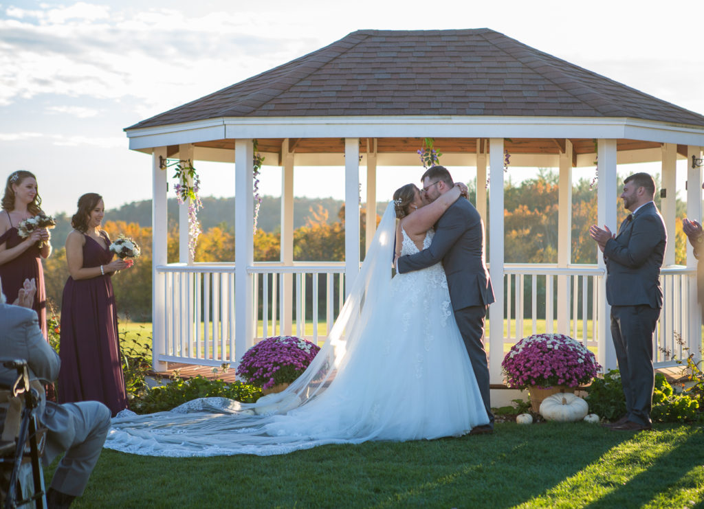 wedding ceremony first kiss as husband and wife in front of the gazebo at the perfect fall wedding