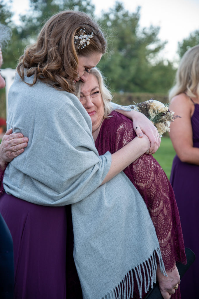 bridesmaid hugging a crying mother of the bride