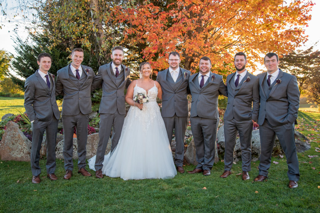 bride and groom with his bridal party in front of the foliage tree at the perfect fall wedding