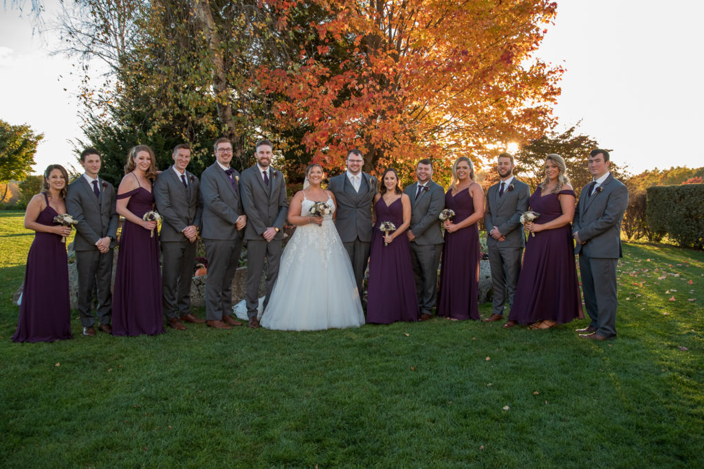 bride and groom with their bridal party in front of the foliage tree at the perfect fall wedding