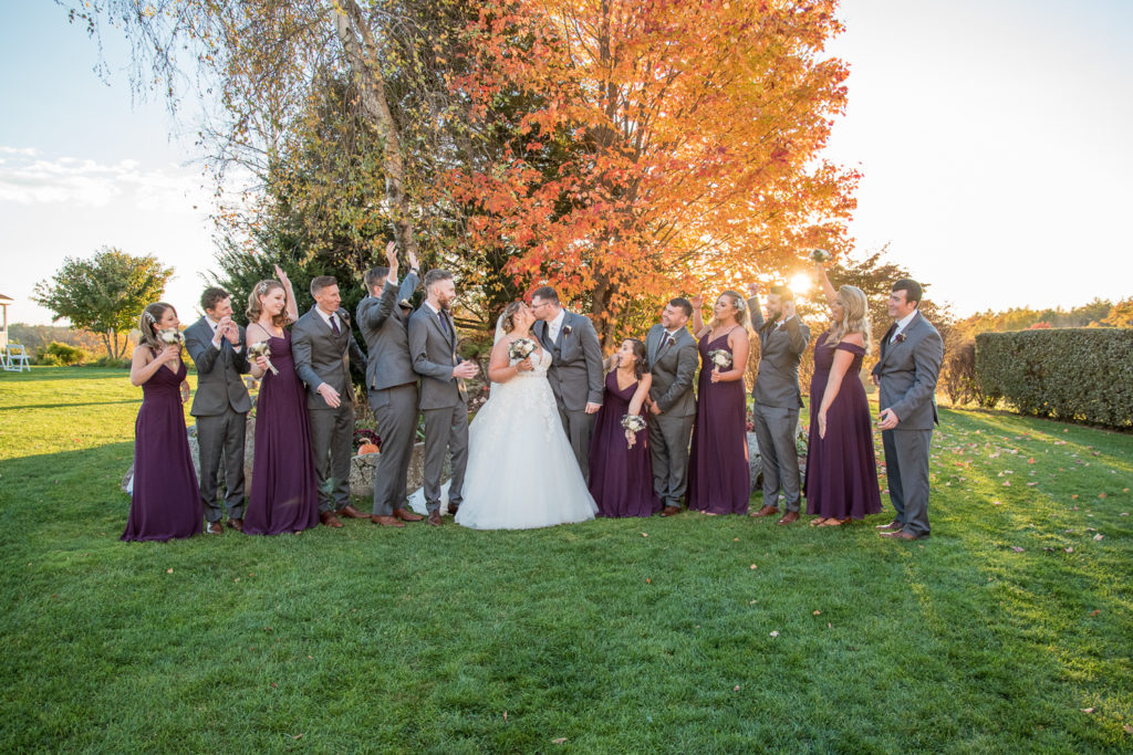 bride and groom with their bridal party in front of the foliage tree at the perfect fall wedding