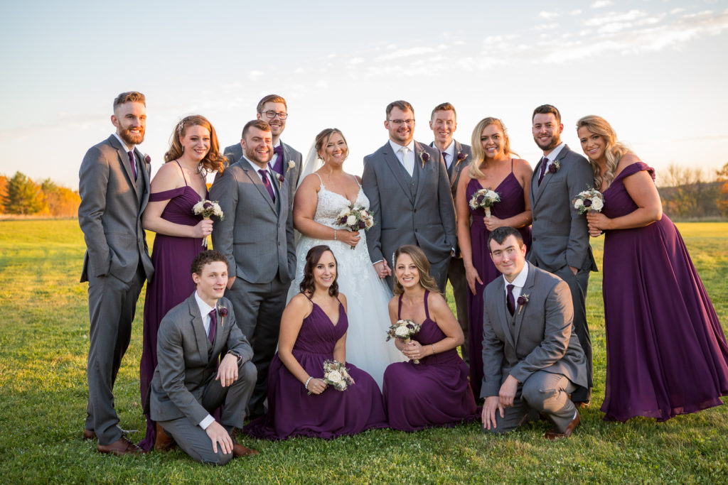 bride and groom with their bridal party in a field at sunset at the perfect fall wedding