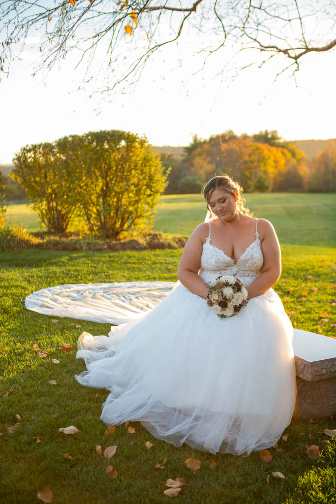 bride sitting on a bench in front of the perfect fall wedding sunset