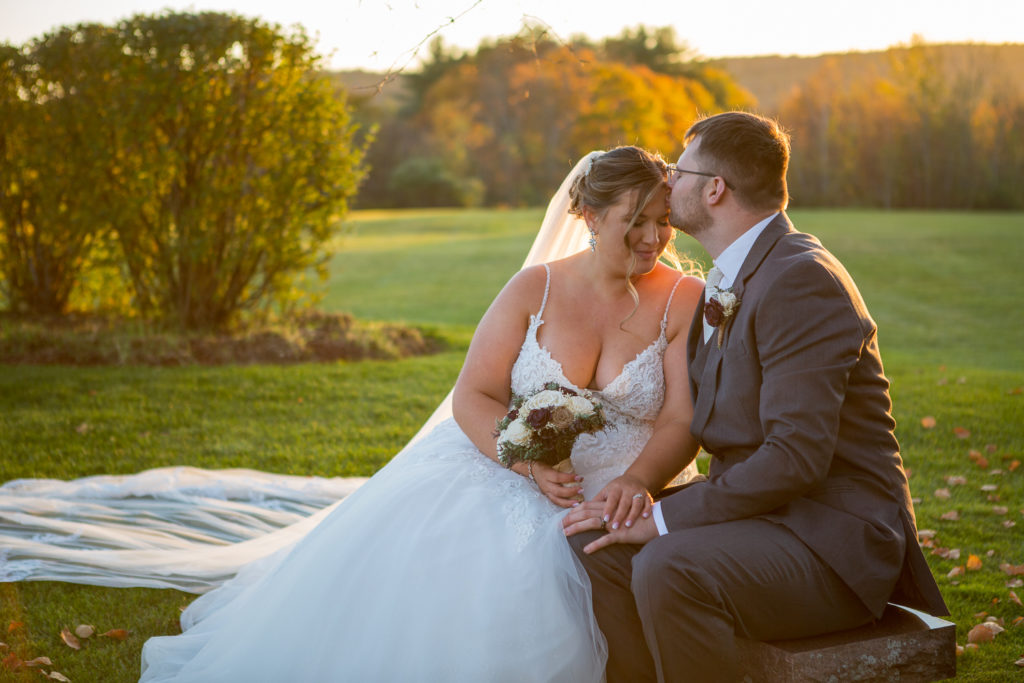 bride and groom sitting on a bench in front of the perfect fall wedding sunset