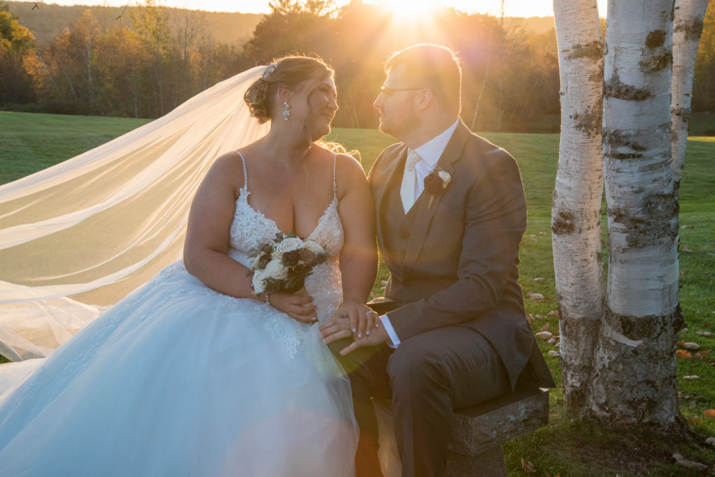 bride and groom sitting on a bench in front of the perfect fall wedding sunset