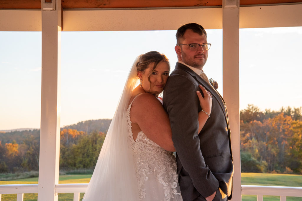 bride hugging groom from behind in the gazebo at sunset at the perfect fall wedding