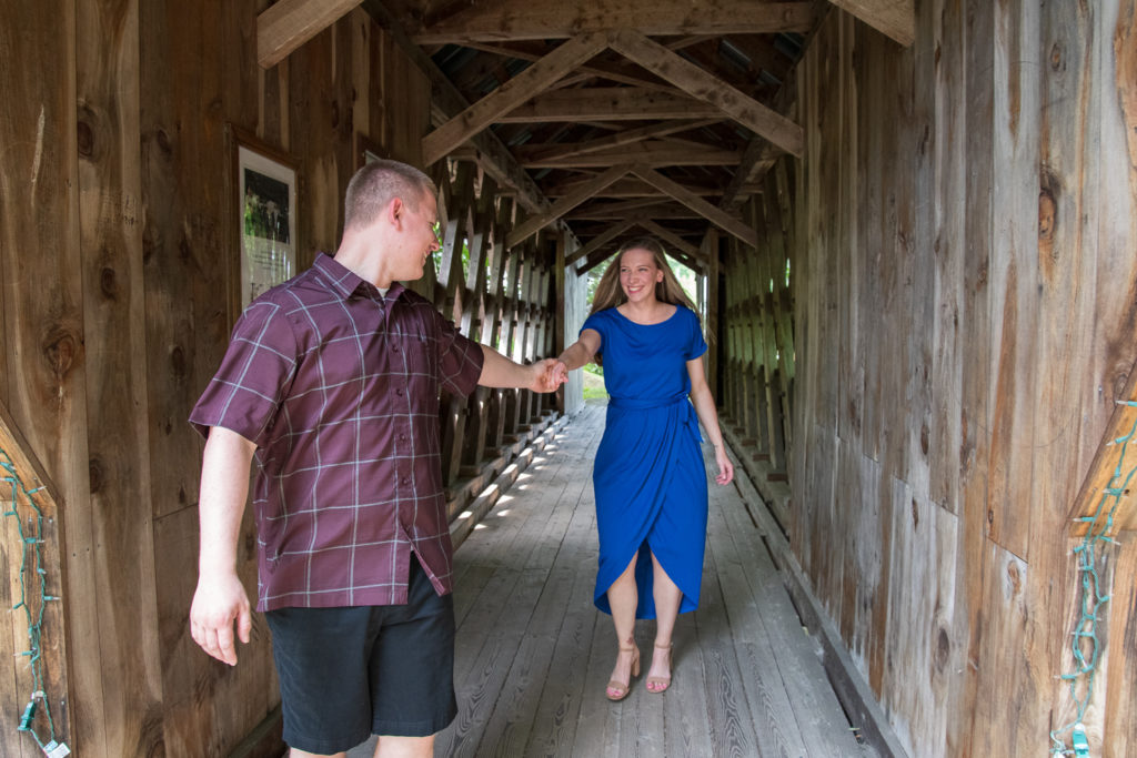 Best of 2021 Engagement groom leading bride hand in hand on covered bridge