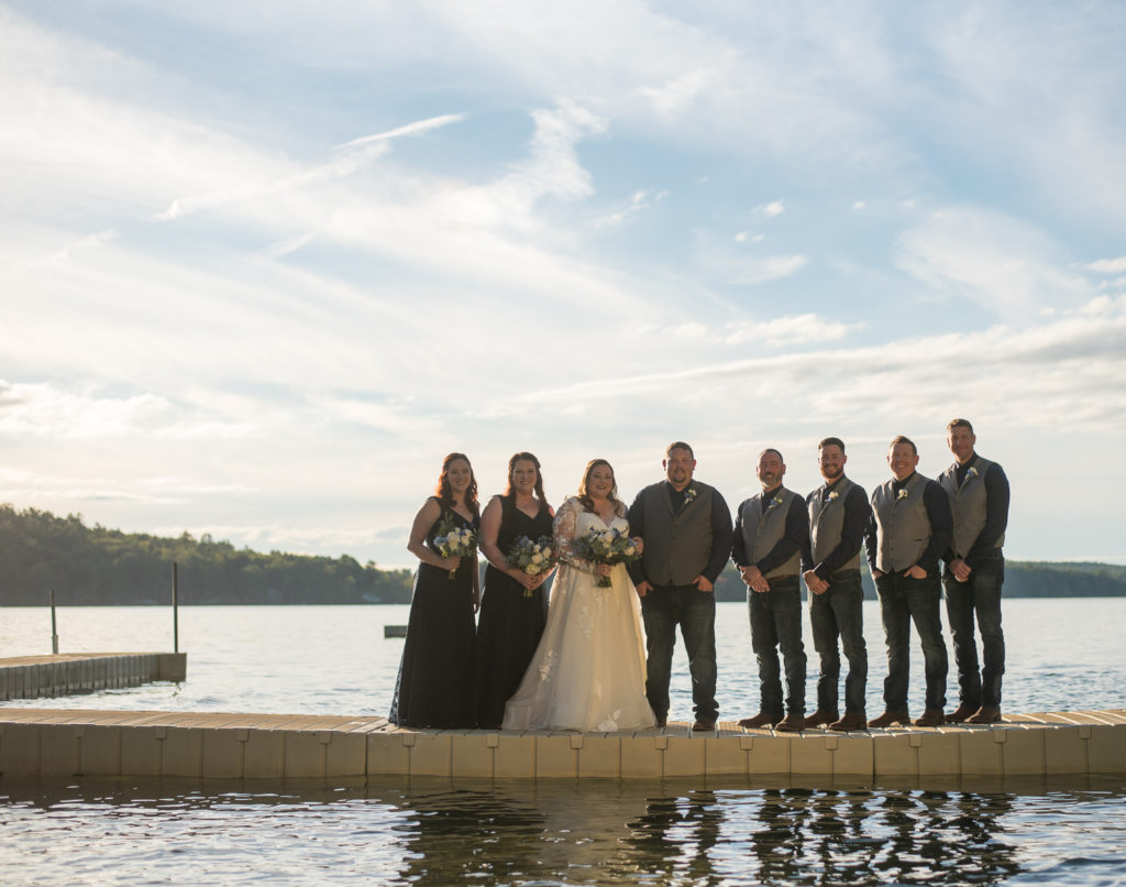 bridal party standing on a dock of Mirror Lake at a fall 2021 wedding in NH