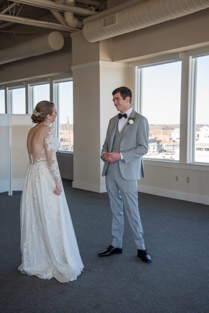 big smile on groom's face as he sees his bride for the first time at winter oceanside wedding 
