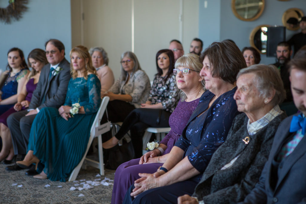 parents of the bride and groom watching the ceremony with tears in their eyes at winter oceanside wedding 