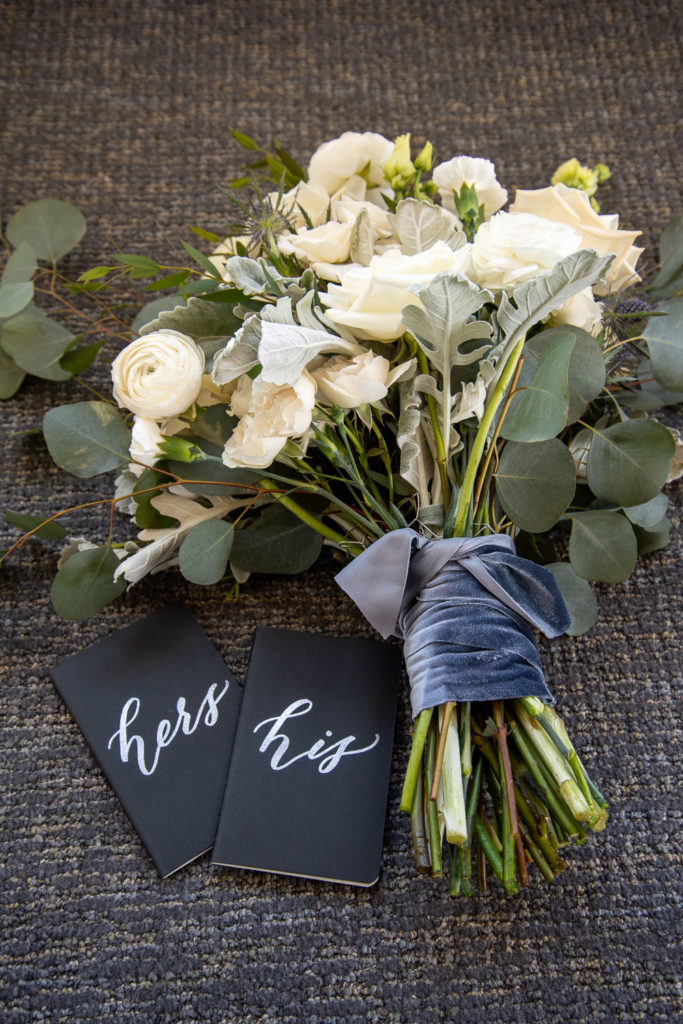 vow books with bridal bouquet at winter oceanside wedding 