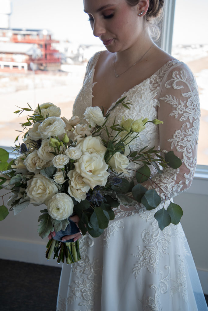 close up of bridal bouquet and lace of wedding dress at winter oceanside wedding 