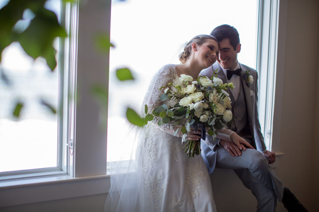 bride and groom snuggling on the window sill after ceremony