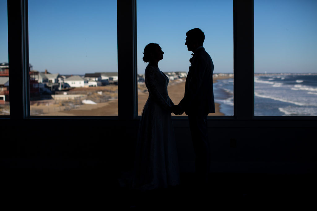 silhouette of bride and groom with ocean in the background at winter oceanside wedding  