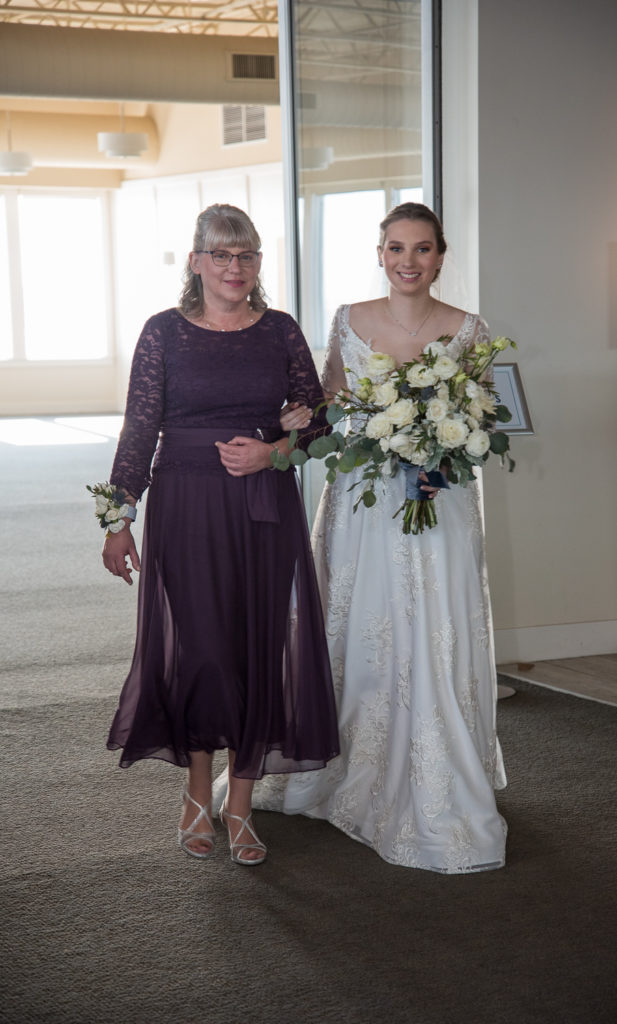 bride and her mom walking down the aisle smiling 