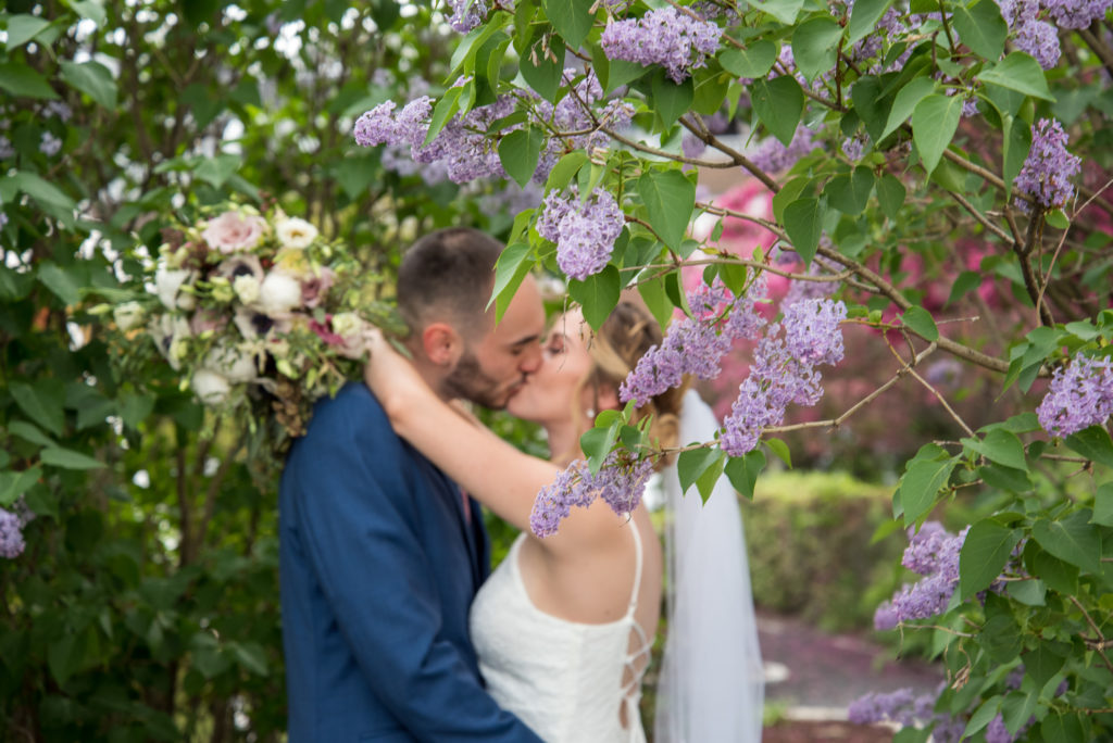 bride and groom kissing behind a lilac branch 2021 spring wedding