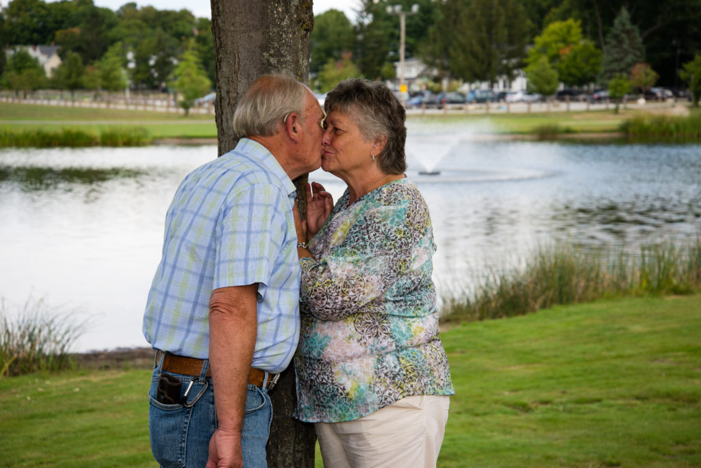 Sixty Years of marriage kissing by a tree in front of fountain