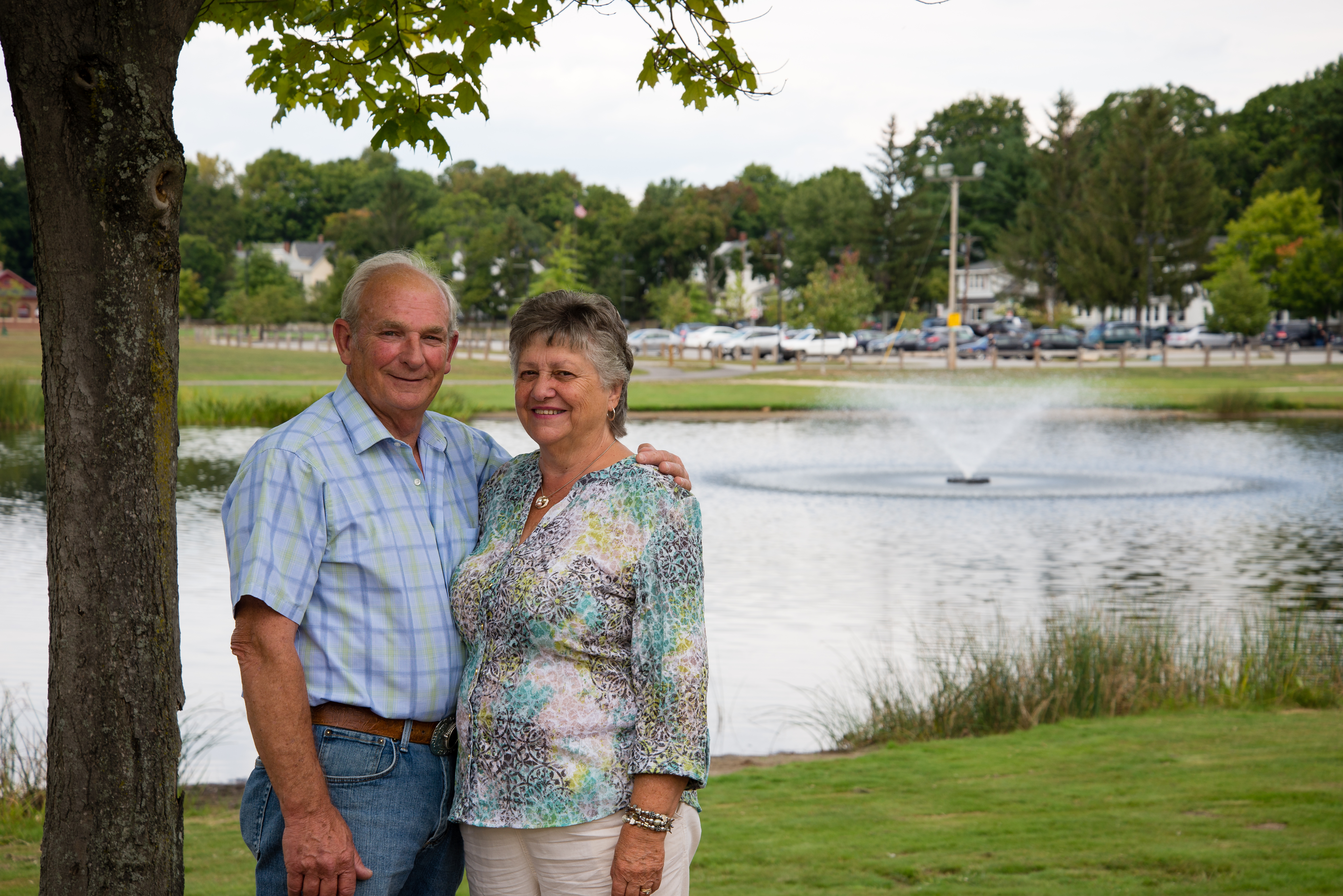 couple standing in front of a pond with a fountain