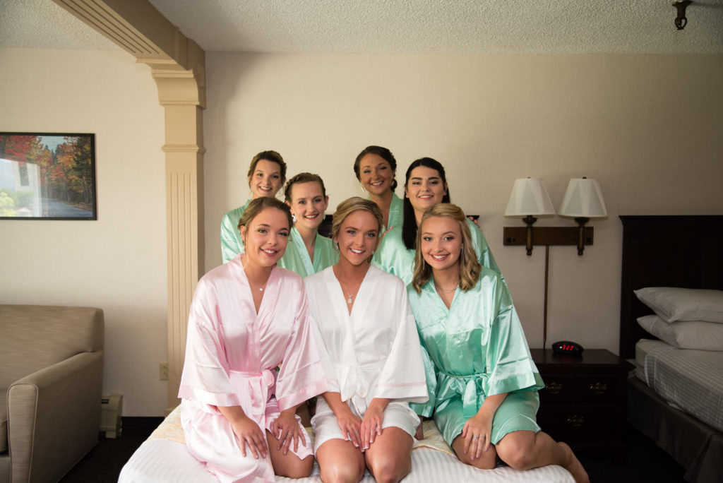 Bride with her bridesmaids sitting on the bed in matching robes