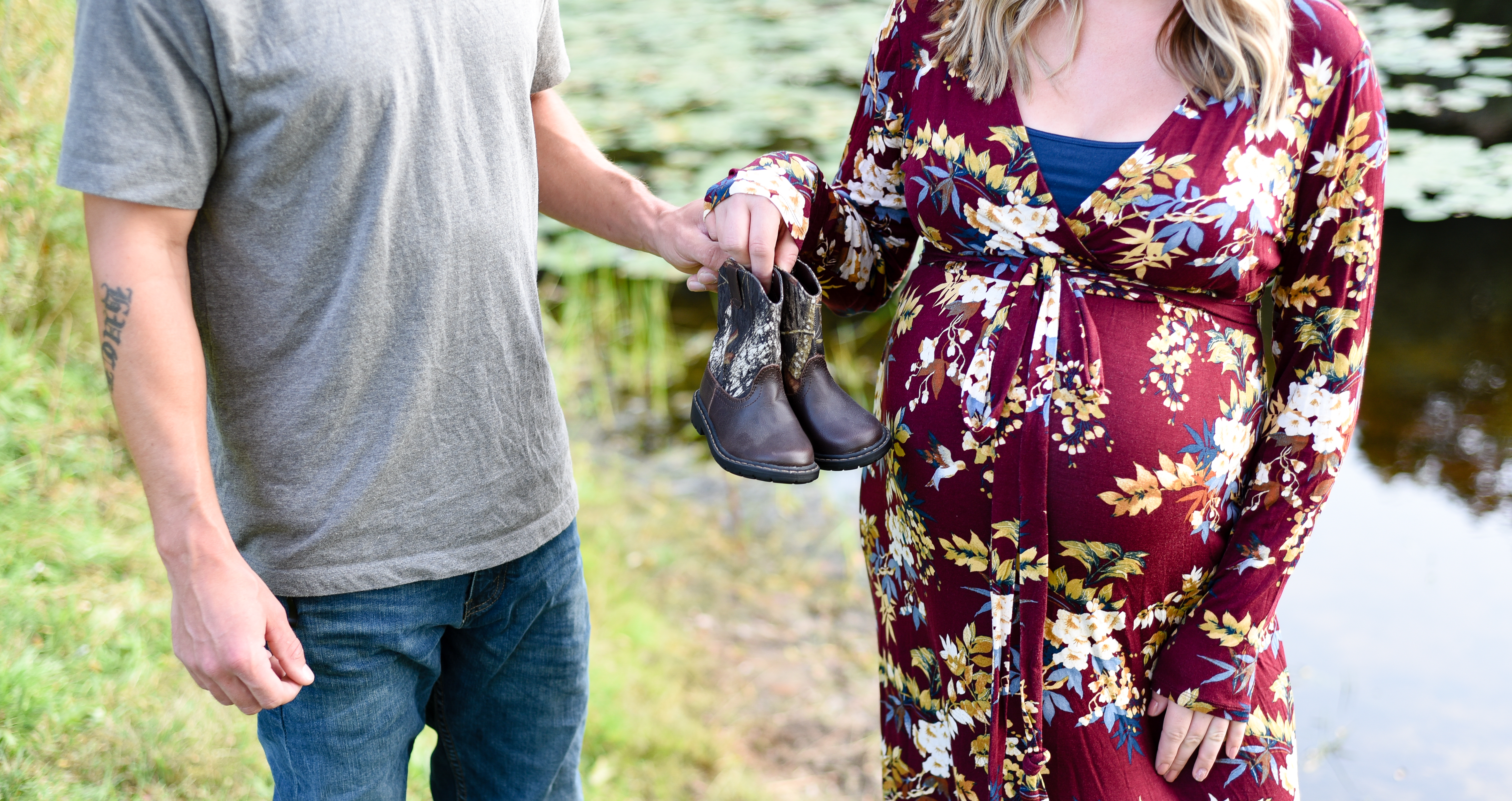 mom and dad to be holidng baby cowboy boots focused up close on belly