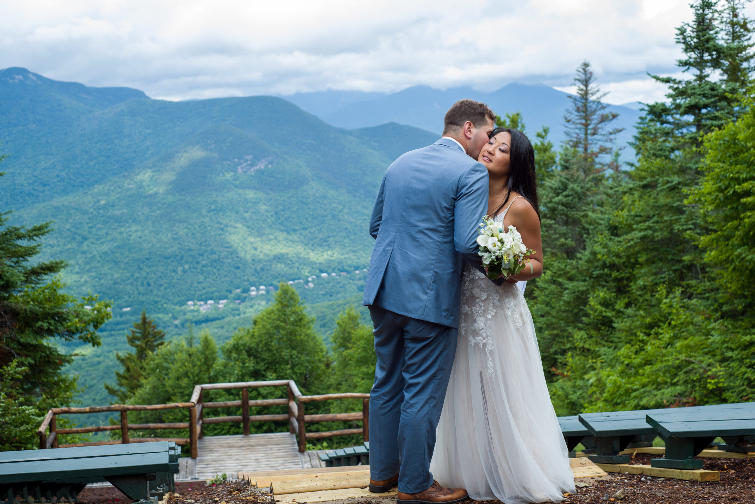 groom whispering into brides ear, bride smiling with the mountains behind them
