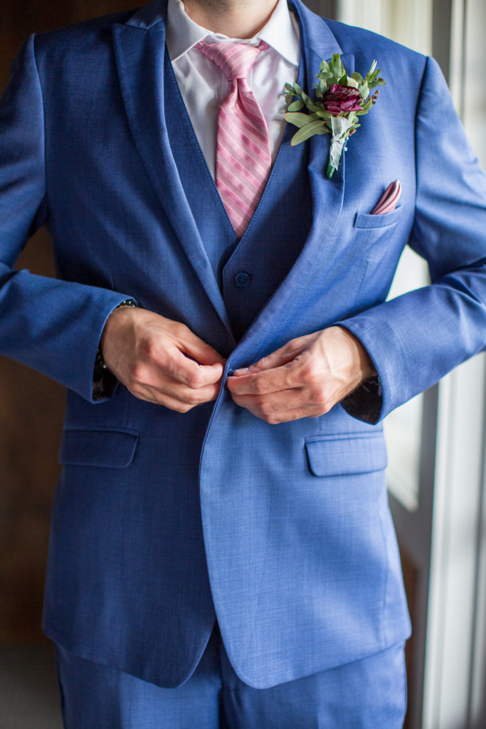 Groom buttoning his jacket