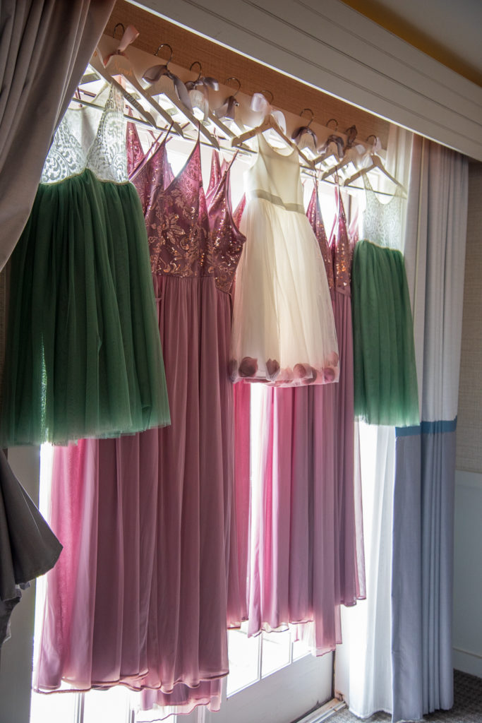 bridesmaids and flower girl dresses hanging up in front of a french door