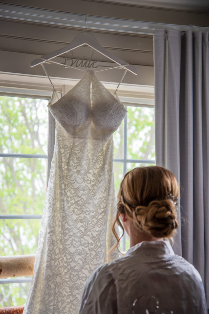 Bride looking at her dress hanging in the window