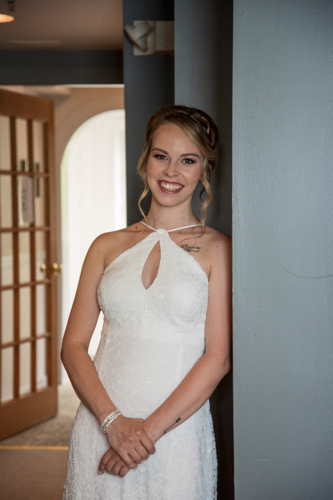 bride leaning against a wall smiling at camera