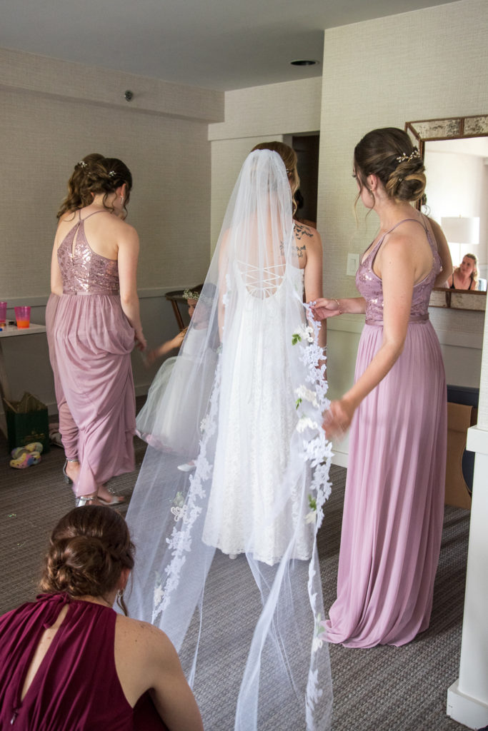 bride putting her veil on with the help of her mom and maid of honors