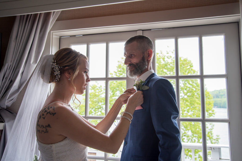 bride putting boutonnière on her dad