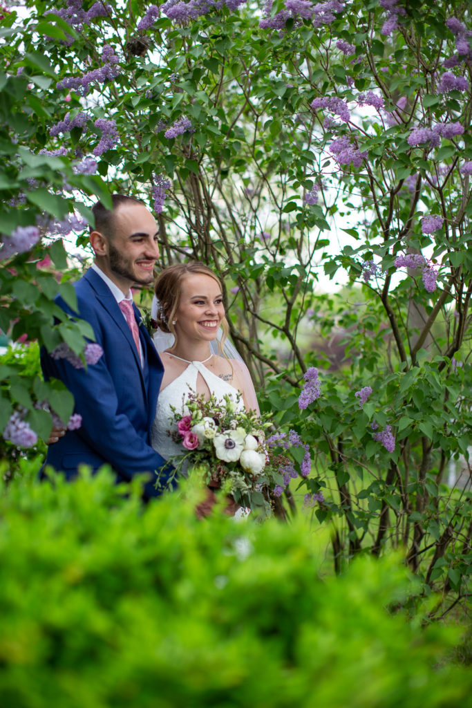 bride and groom posing in lilacs