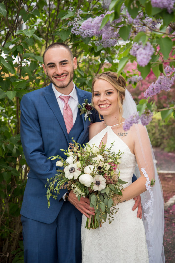 bride and groom posing with lilacs