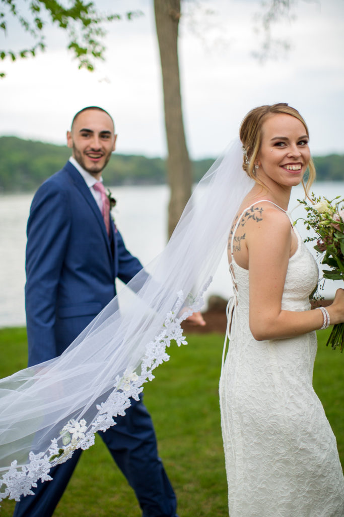 bride and groom walking while smiling at the camera 