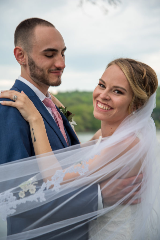 bride smiling at camera while groom looks at bride