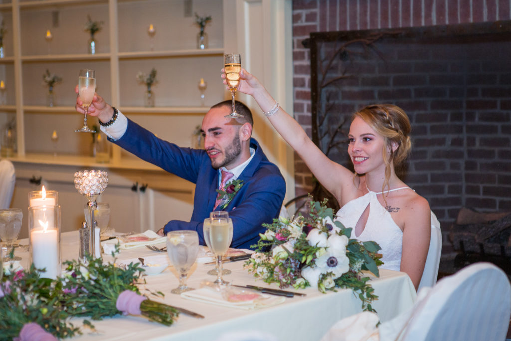bride and groom holding up their glasses to cheers from the wedding toasts