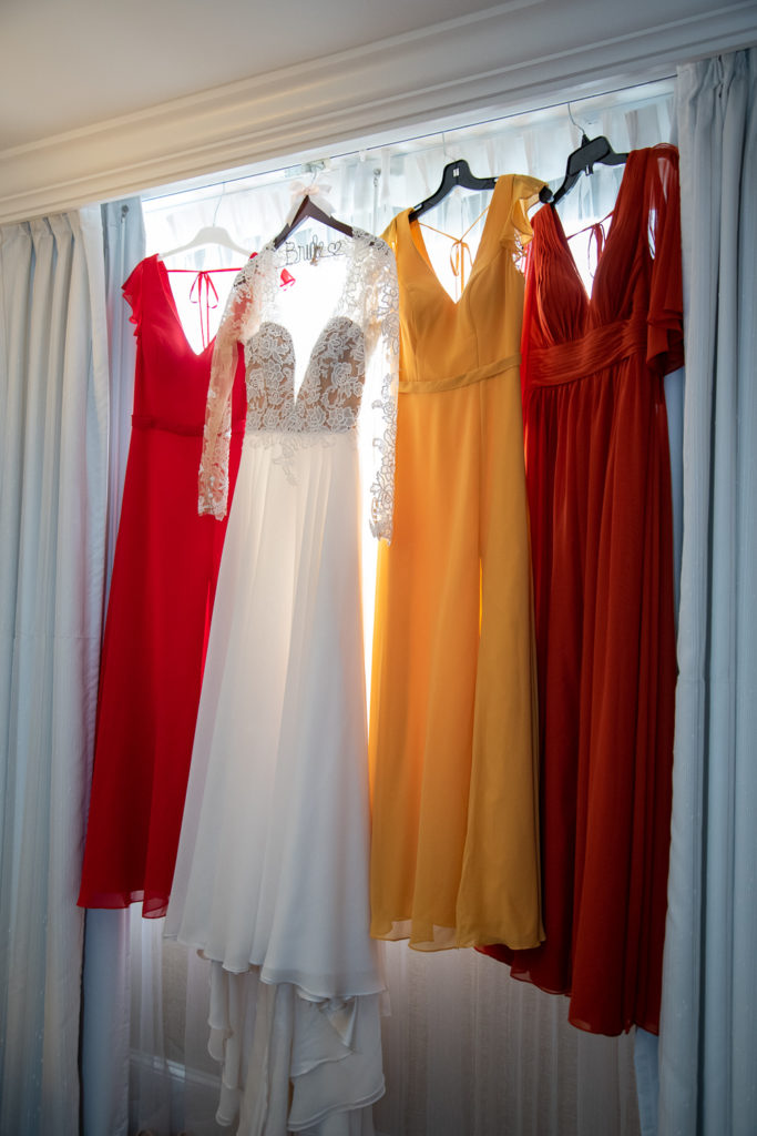 bride and bridesmaid's dresses hanging in the window shot by NH wedding Photographer