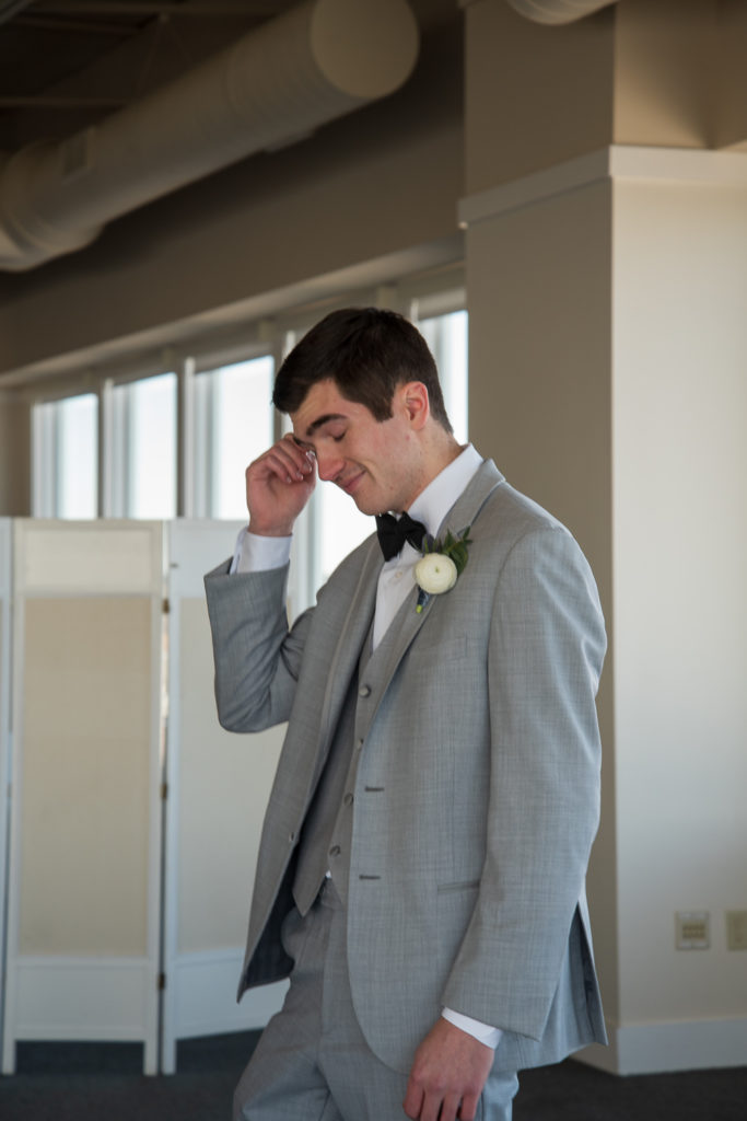 groom wiping a tear from his eye at the first look after seeing his bride